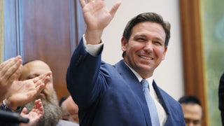 A smiling Ron DeSantis waves to a crowd.