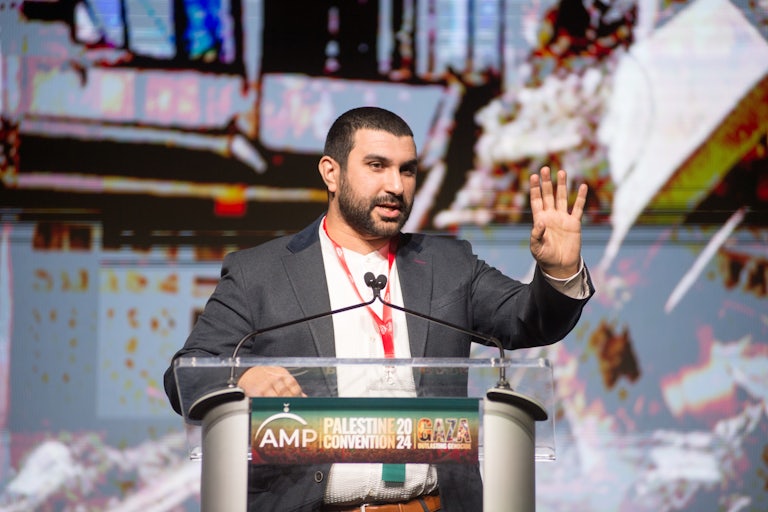Sami Hamdi speaks at a lectern that “reads Palestine Convention 2024 Gaza.”