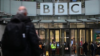 A man walks in front of the BBC headquarters.
