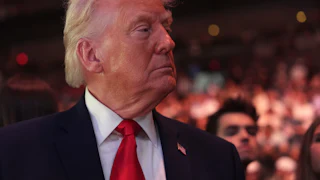 Donald Trump turns his head to the side while standing in the audience at a UFC match