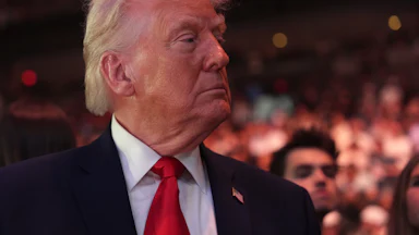 Donald Trump turns his head to the side while standing in the audience at a UFC match