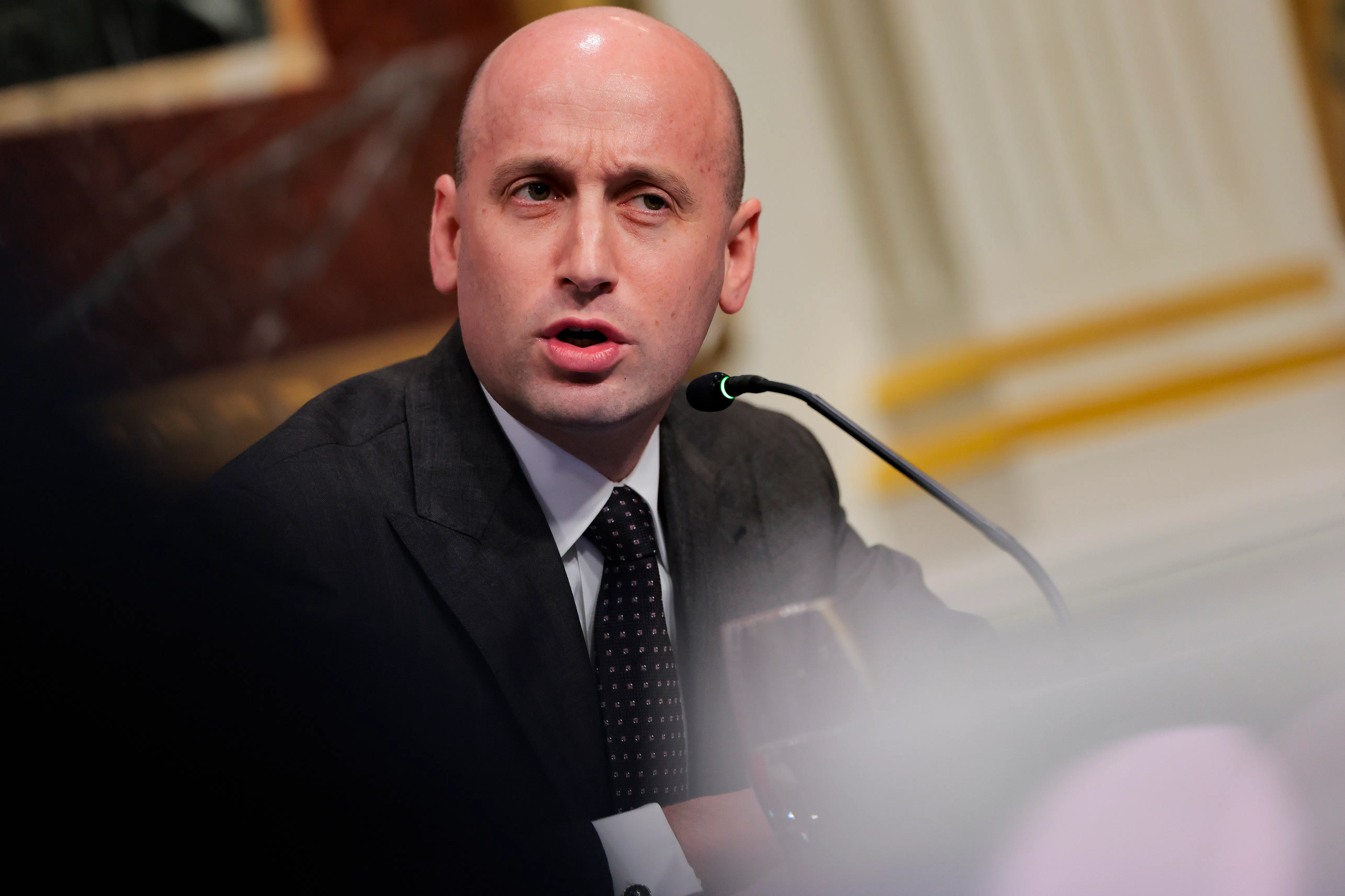 Stephen Miller frowns and speaks into a microphone