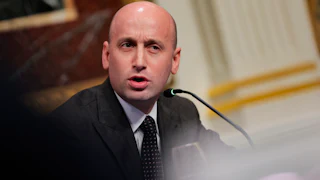 Stephen Miller frowns and speaks into a microphone