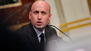 Stephen Miller frowns and speaks into a microphone