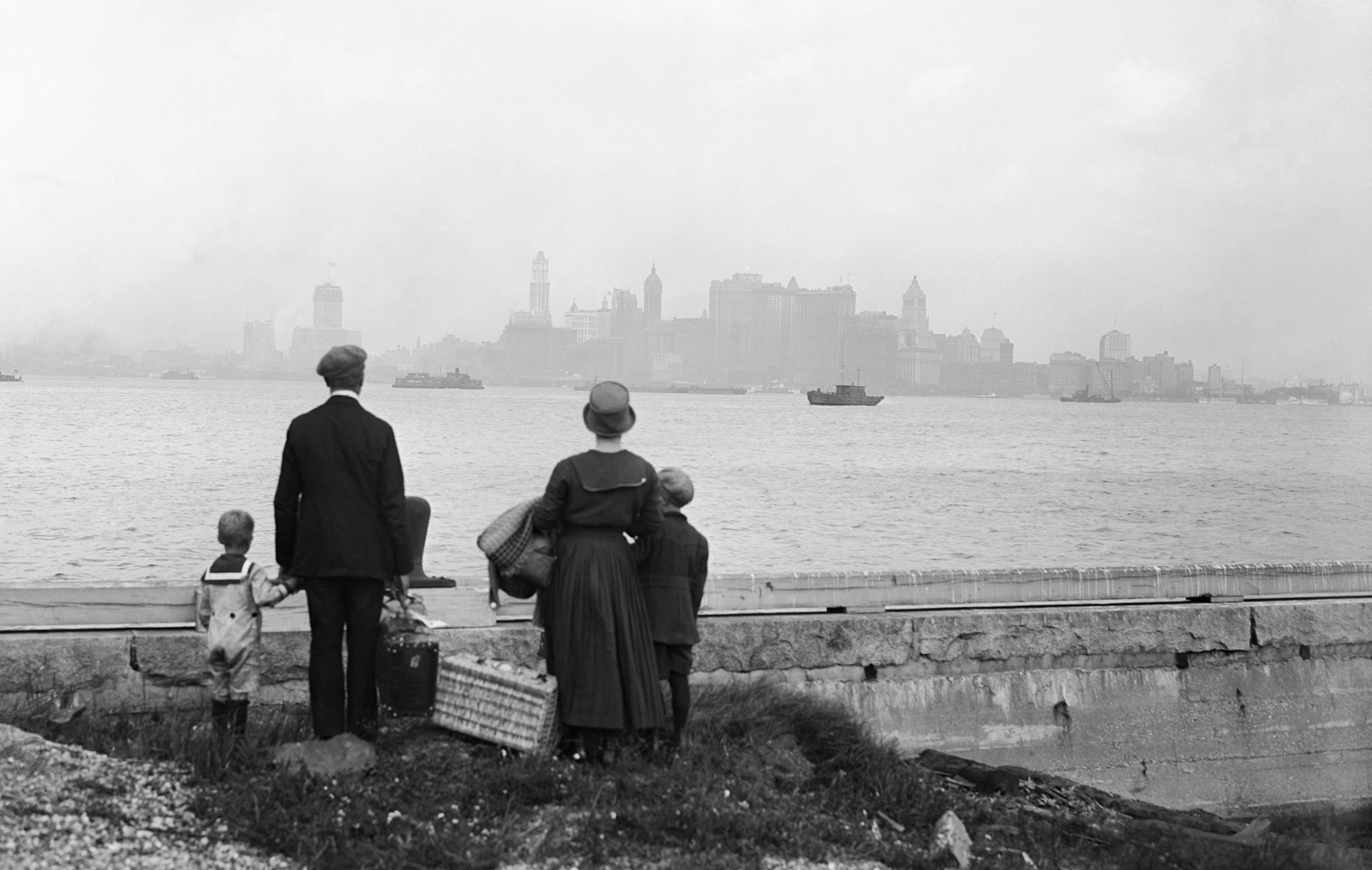An immigrant family views the New York skyline from the dock at Ellis Island in 1925.