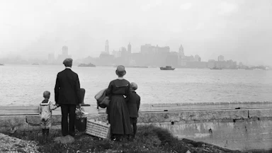 An immigrant family views the New York skyline from the dock at Ellis Island in 1925.