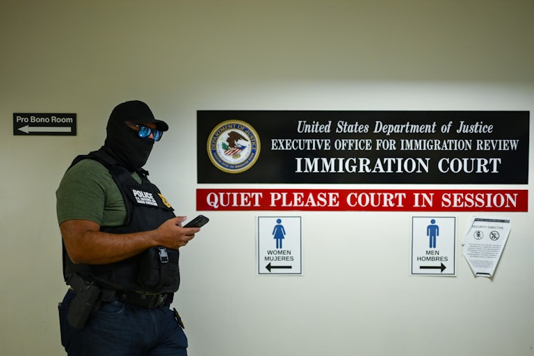 A masked agent looks at his phone in immigration court.