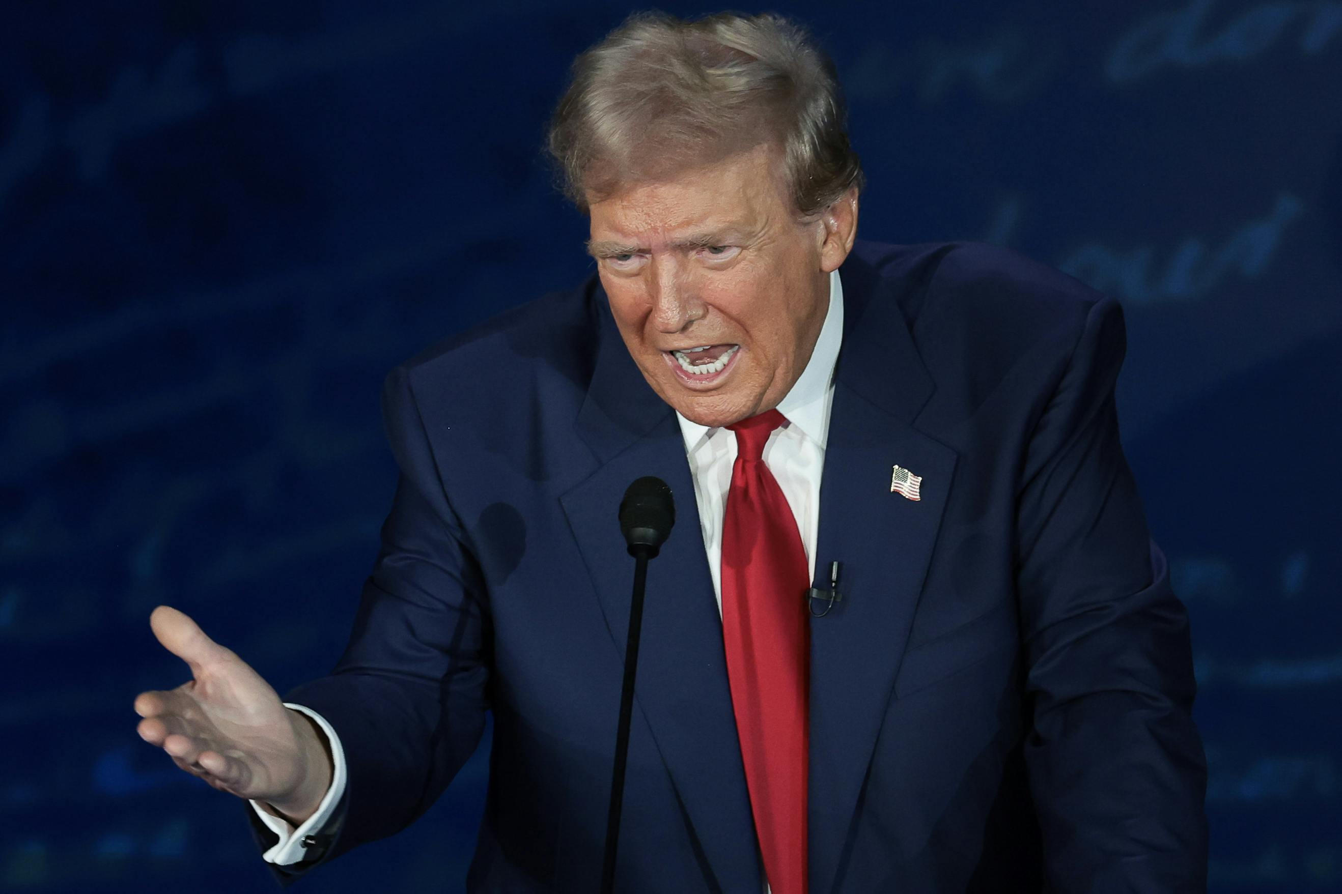 Donald Trump gestures with one hand while speaking into a microphone.