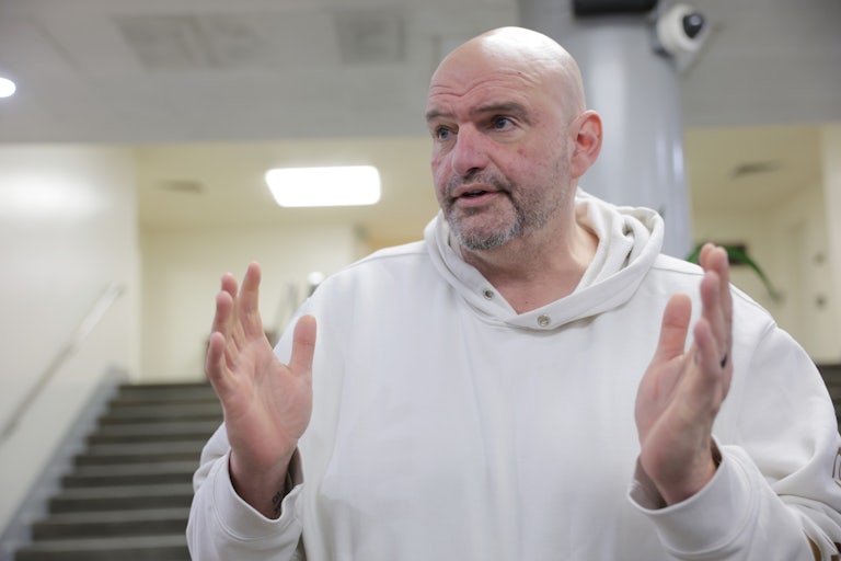 Pennsylvania Senator John Fetterman raises both hands while speaking to reporters.