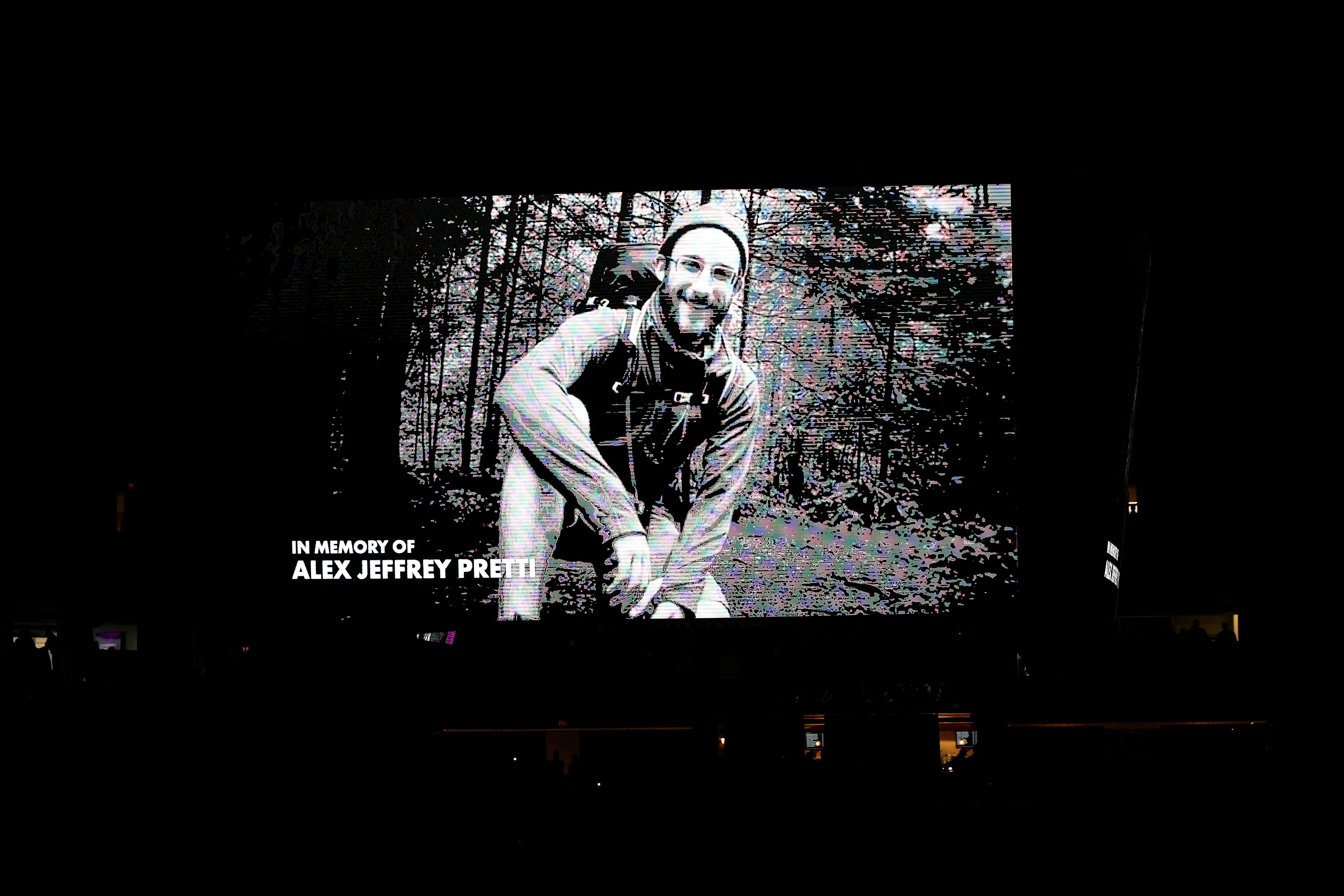 Black and white photo of Alex Pretti hiking in the woods appears on a large screen with the words "In memory of Alex Jeffrey Pretti"