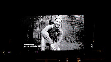 Black and white photo of Alex Pretti hiking in the woods appears on a large screen with the words "In memory of Alex Jeffrey Pretti"