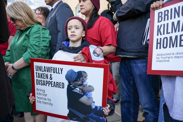 A child holds a sign reading "Unlawfully Taken & Disappeared" with a photo of Kilmar Abrego Garcia holding a child. Another person next to him holds a sign reading "Bring Kilmar Home."