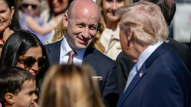 Stephen Miller speaks with Donald Trump in a crowd fo people