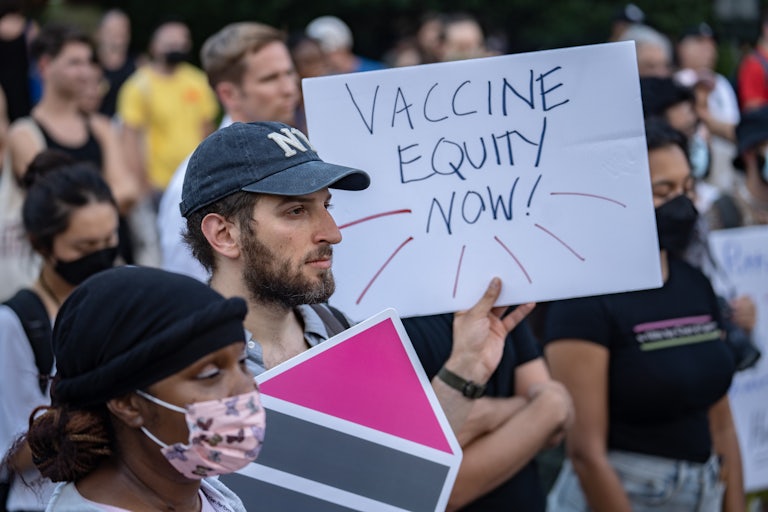 A protester holds a sign saying "vaccine equity now!"