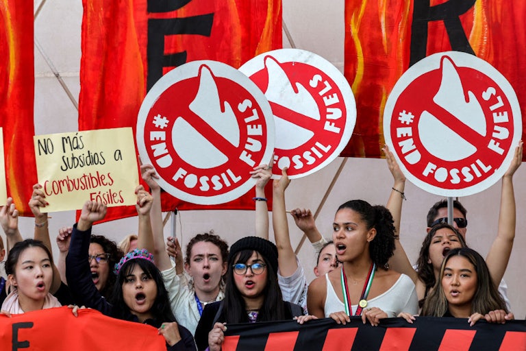 Activists hold signs reading "End Fossil Fuels."