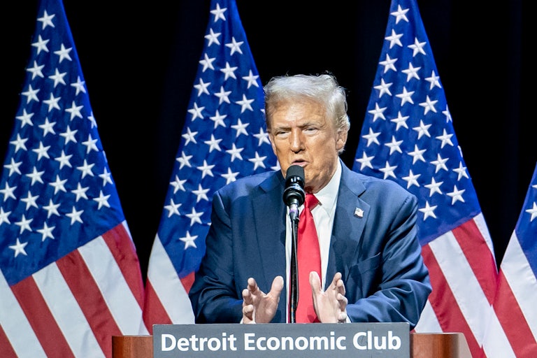 Donald Trump gestures while speaking at a podium at the Detroit Economic Club