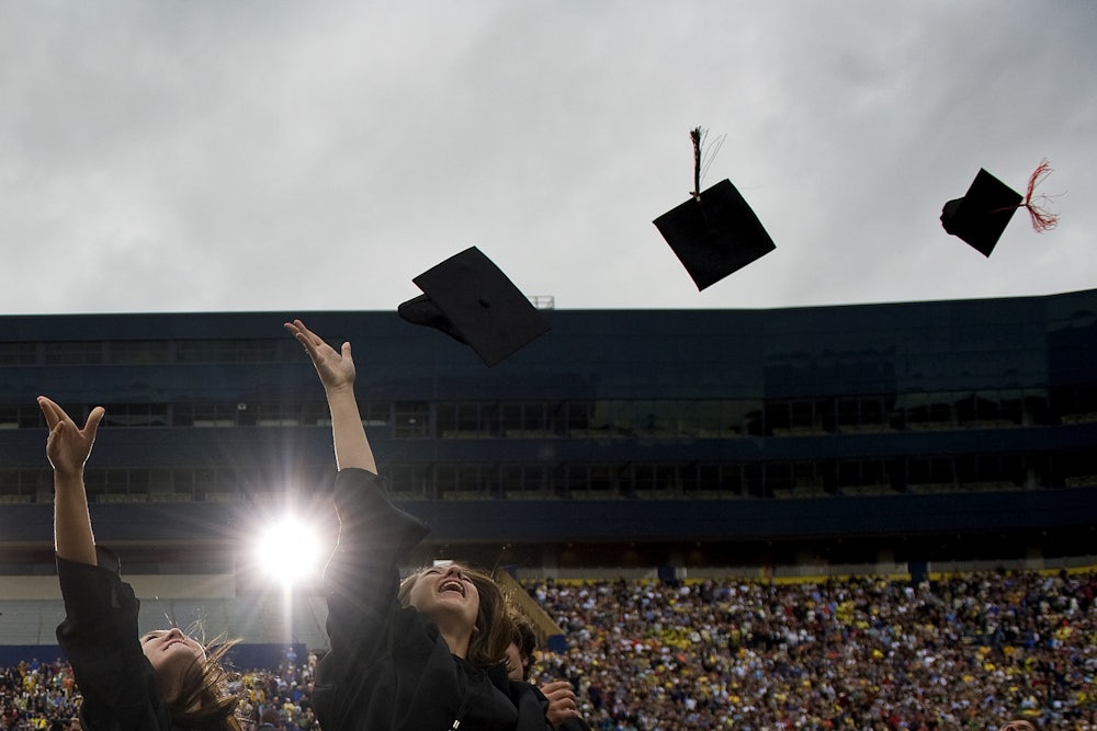 Graduates throw their mortarboards into the air.