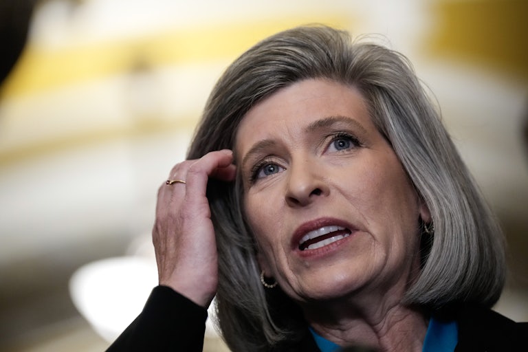 Senator Joni Ernst brushes her hair out of her face while speaking.