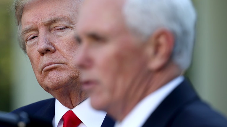 Mike Pence's blurry head appears in the foreground as President Donald Trump looks on from behind.