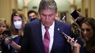 West Virginai Senatro Joe Manchin glances downward as he's trailed by reporters through Capitol Hill.