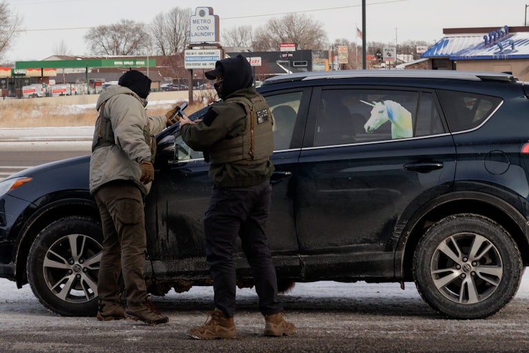 Federal immigration agents stand outside a car with a unicorn on it.