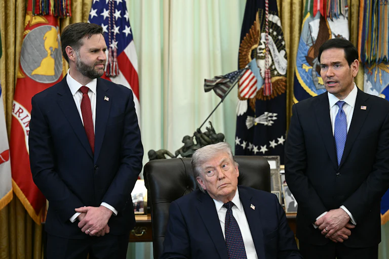 President Donald Trump sits at his desk in the Oval Office, while Vice President JD Vance and Secretary of State Marco Rubio stand behind him.