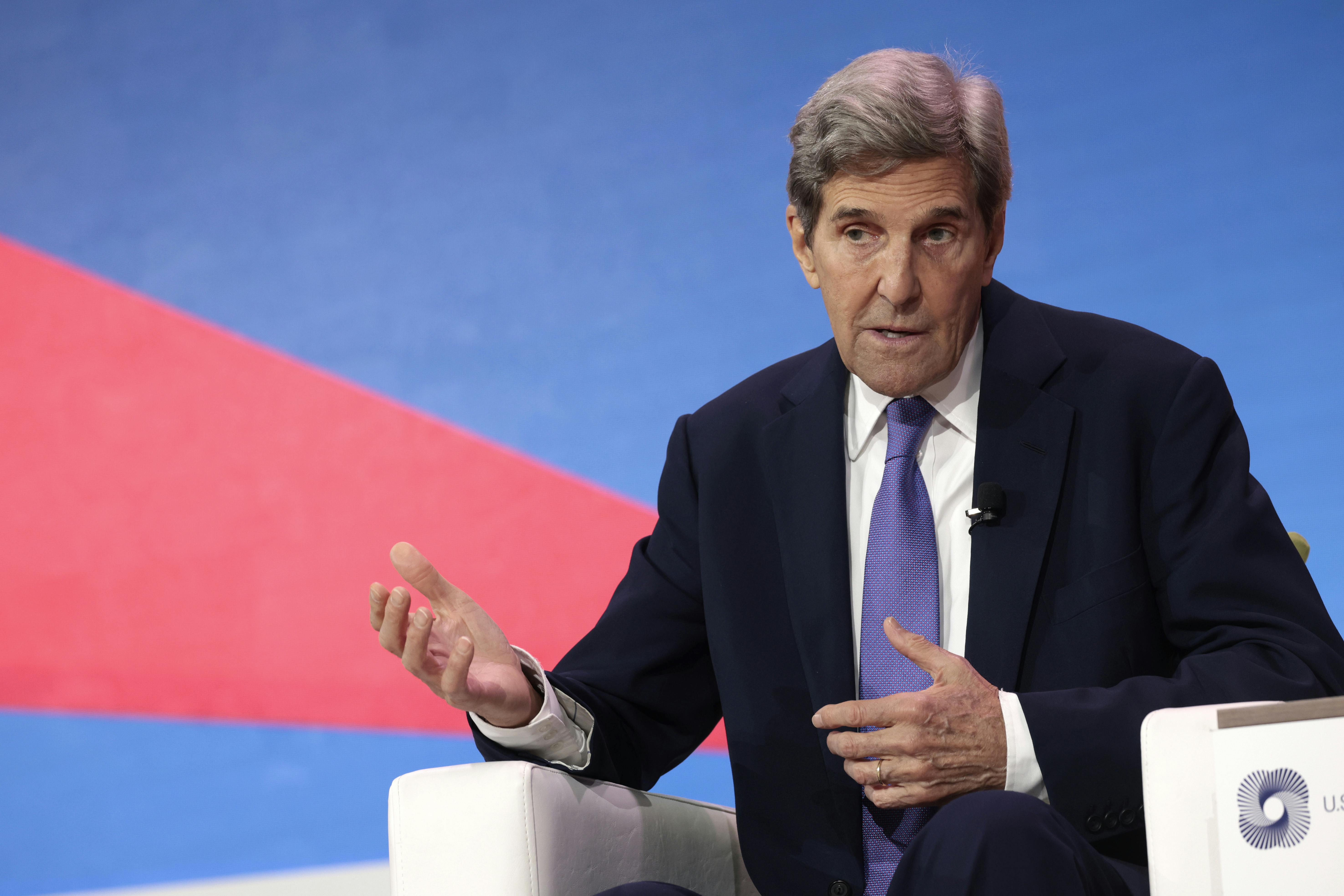 John Kerry gesticulates while speaking, seated.