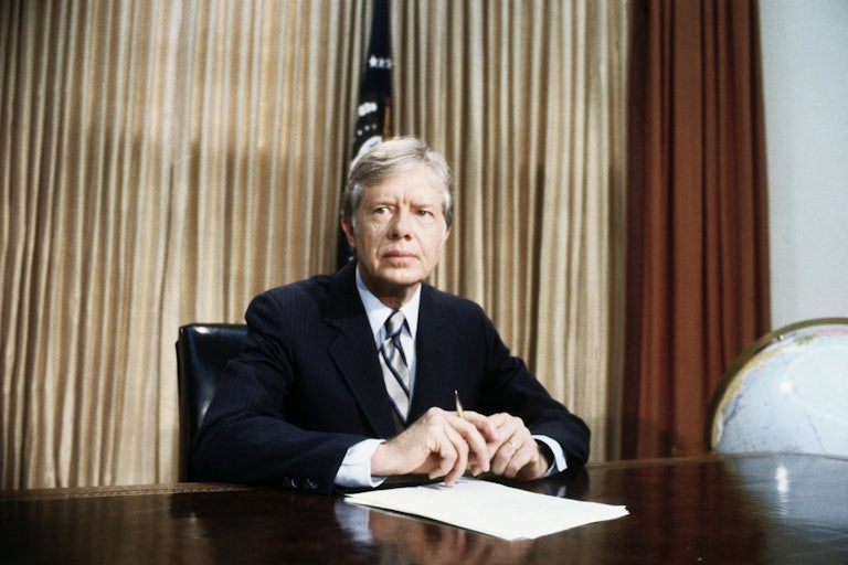 President Jimmy Carter sits at his desk in the Oval Office