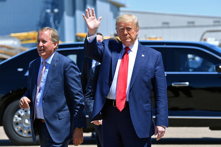 Donald Trump waves to the camera as Ken Paxton smiles and walks beside him. A black car is behind them.
