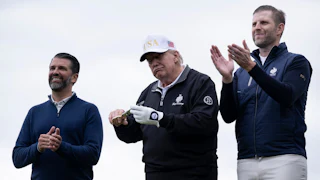 Donald Trump Jr. and Eric Trump clap and smile while flanking their father on a golf course