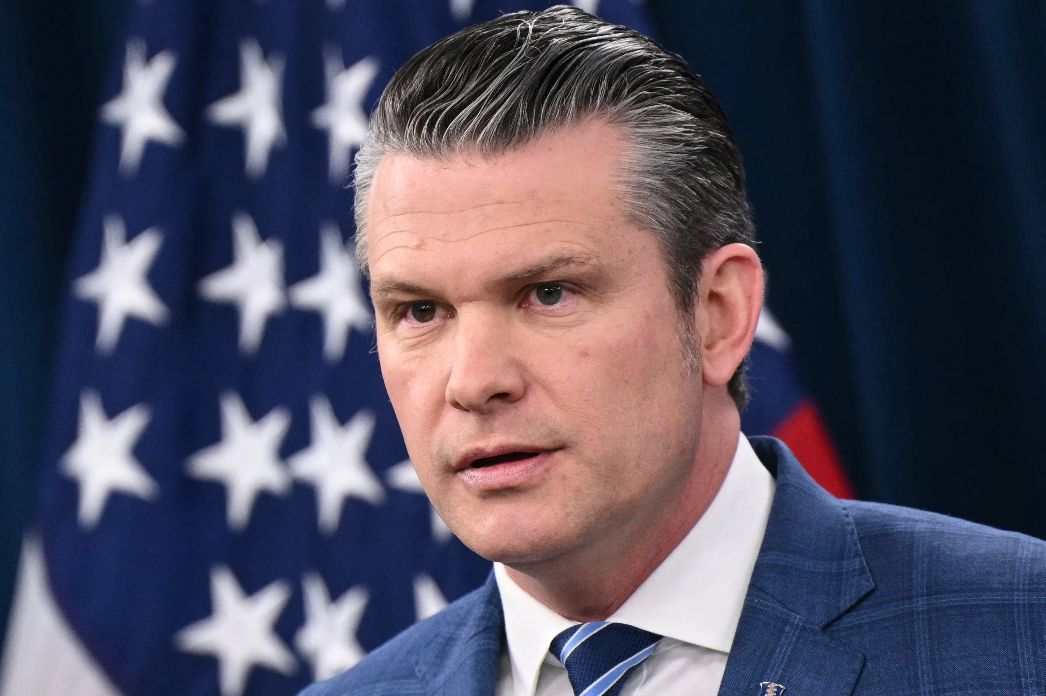 Pete Hegseth stares while answering media questions