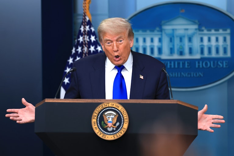 Donald Trump holds his hands out to the side while speaking at the podium in the White House press briefing room