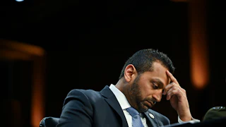 FBI Director Kash Patel leans forward and puts his head in his hand during a congressional hearing.