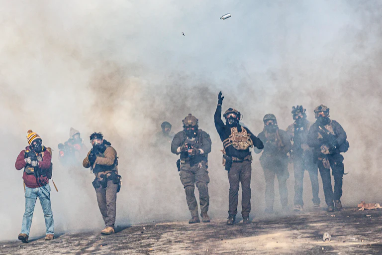 heavily armed federal agents walk through tear gas they've deployed in minnesota
