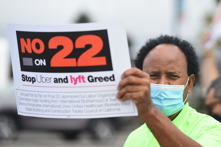 A rideshare driver holds up a sign supporting a no vote on Prop 22