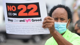 A rideshare driver holds up a sign supporting a no vote on Prop 22