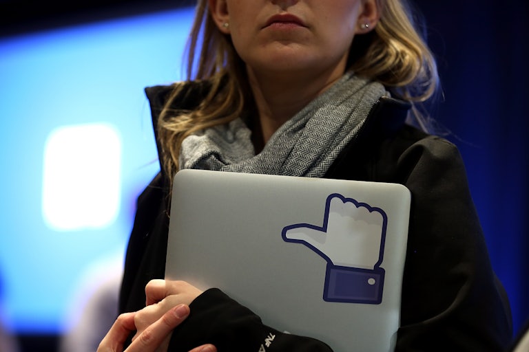 A Facebook employee holds a laptop with a "like" sticker on it.
