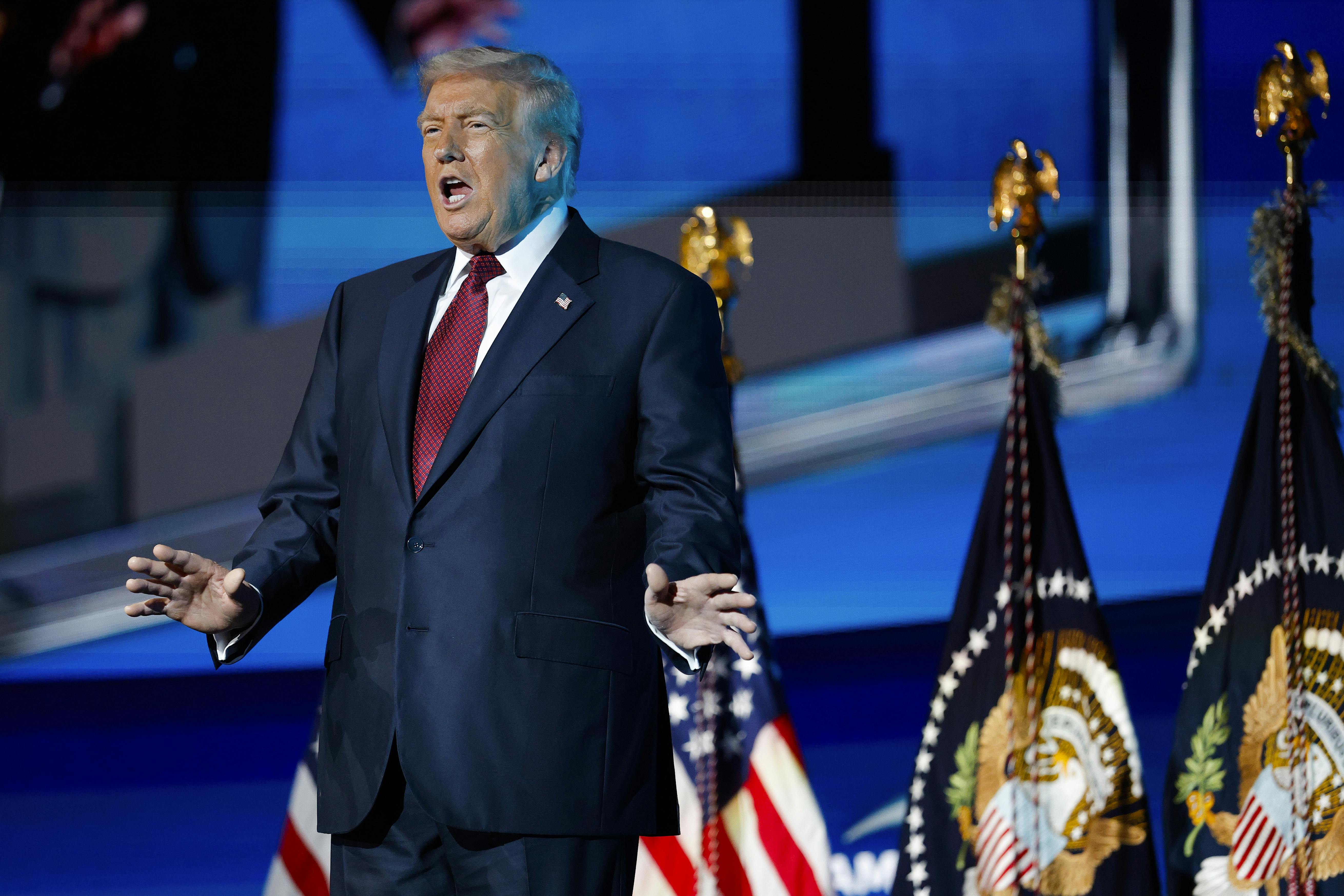 Donald Trump holds his hands out to the side while speaking on stage