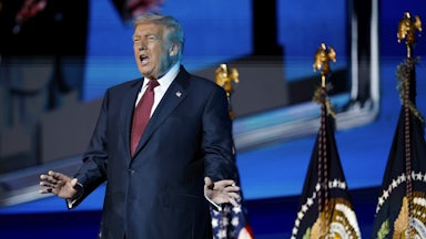 Donald Trump holds his hands out to the side while speaking on stage