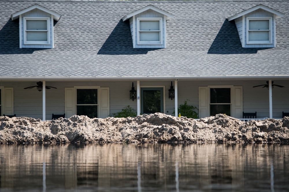 A levee holds back water in front of a house.