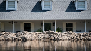 A levee holds back water in front of a house.