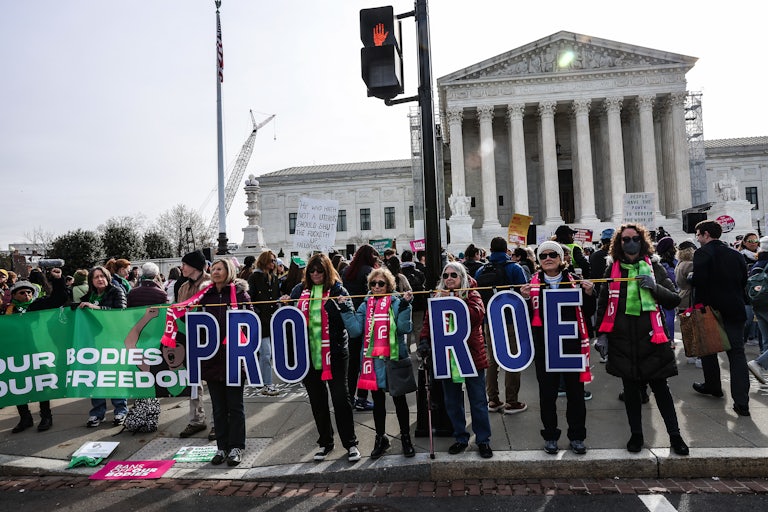 Protesters outside the Supreme Court hold banners that say "Our Bodies Our Freedom" and "Pro Roe."