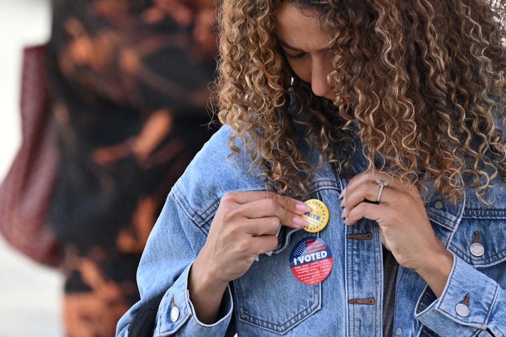 A young woman attaches a pin to her jacket after voting at a mobile outdoor vote center at SoFi Stadium in Los Angeles, California.