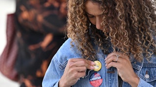 A young woman attaches a pin to her jacket after voting at a mobile outdoor vote center at SoFi Stadium in Los Angeles, California.