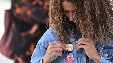 A young woman attaches a pin to her jacket after voting at a mobile outdoor vote center at SoFi Stadium in Los Angeles, California.