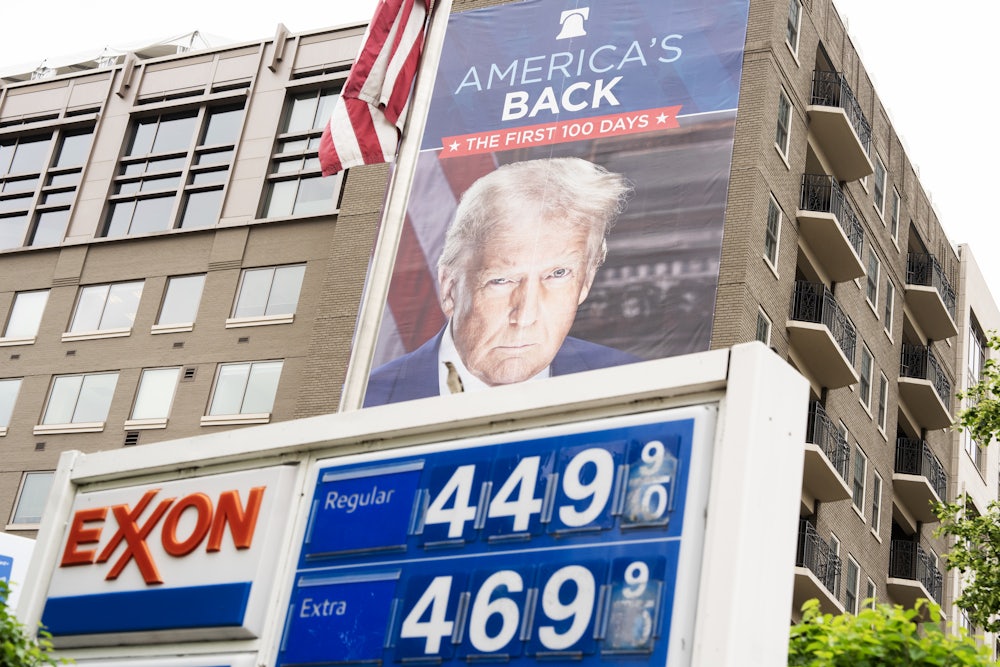 An image of President Donald Trump, marking his first 100 days in office, is seen on a poster sponsored by the Heritage Foundation, next to an Exxon station on Capitol Hill.