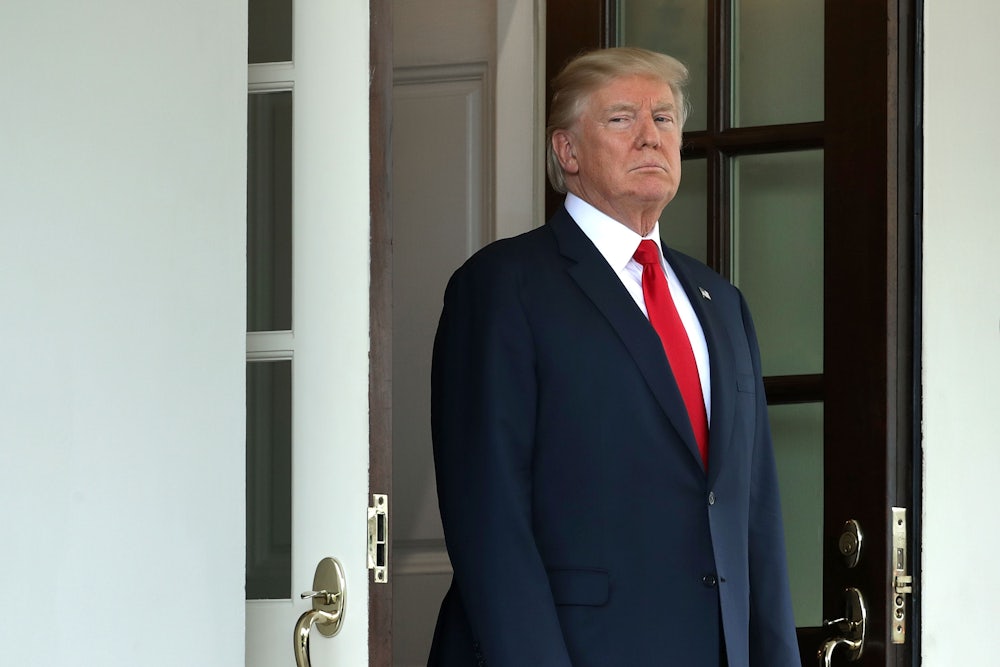 A glowering President Donald Trump stands in the door of the White House.