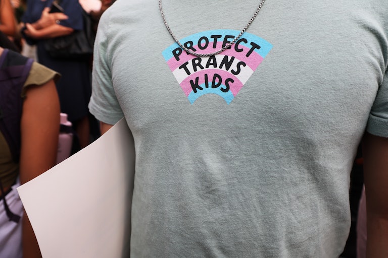 A close-up of someone's T-shirt, which has a trans flag with the text "Protect Trans Kids."