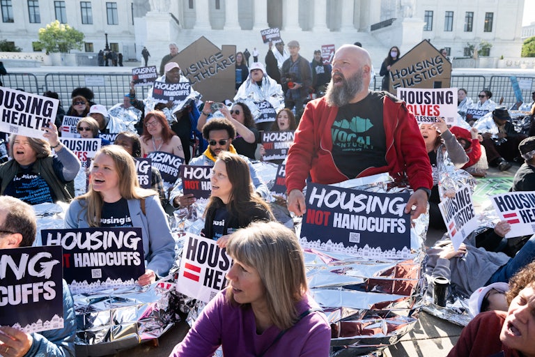 People protest outside the Supreme Cour twith signs that read "Housing not handcuffs"