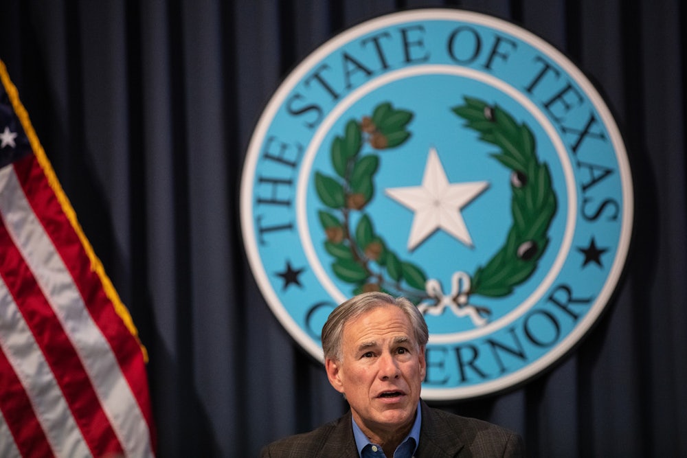 Texas Governor Greg Abbott sits in front of the Texas State Seal.